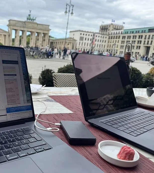 Zwei aufgeklappte Notebooks auf einem Cafétisch, dahinter das Brandenburger Tor