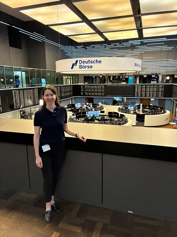 Eine Frau an der Brüstung über dem Handelssaal, darüber das Schild der Deutschen Börse
