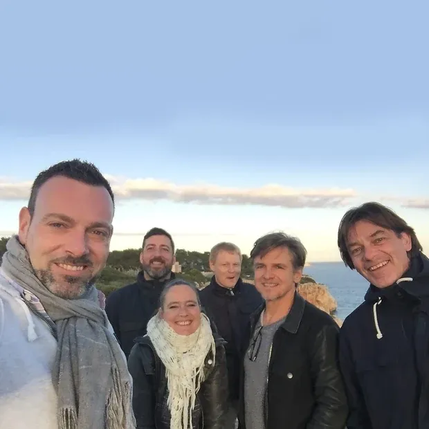 Selfie von sechs Personen an einer Steilküste, dahinter das Meer im Abendlicht