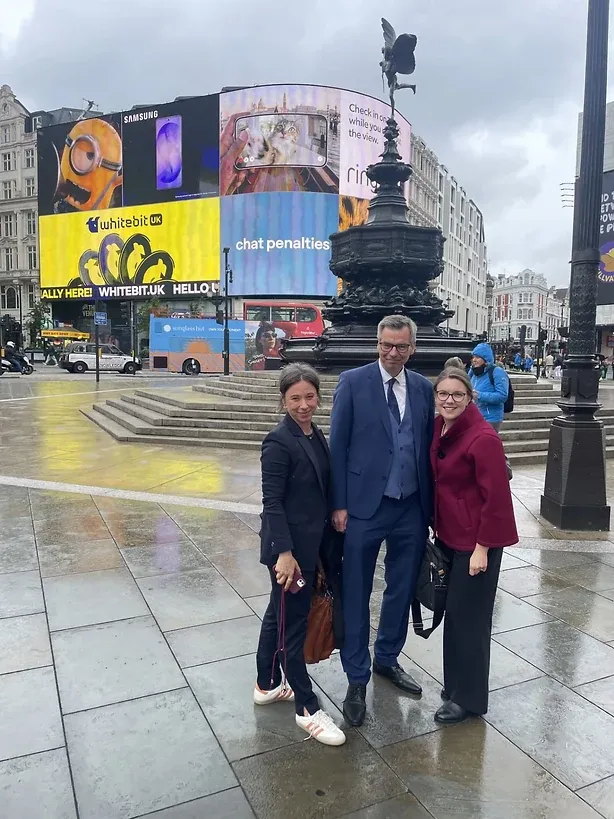 Drei Personen bei Regen am Piccadilly Circus vor den Leuchtreklamen