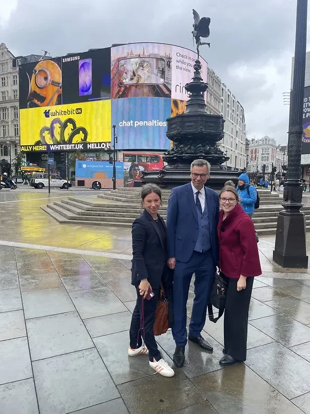 Drei Personen bei Regen am Piccadilly Circus vor den Leuchtreklamen
