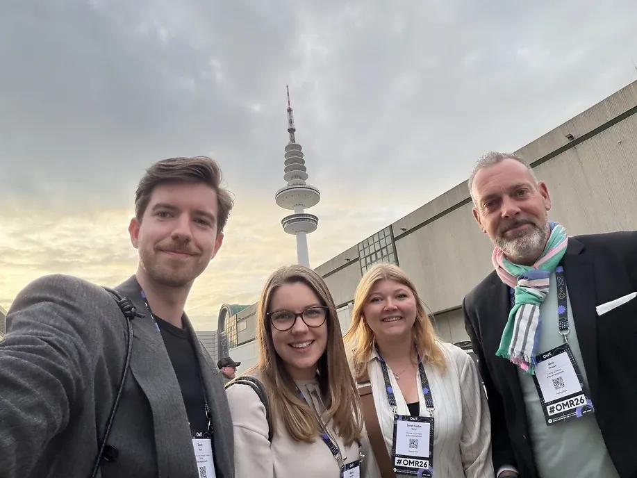 Selfie von vier Personen mit Messeausweisen im Abendlicht, dahinter der Hamburger Fernsehturm